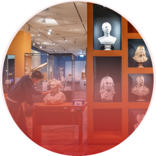 Shelf and table displaying several busts in the German Historical Museum, with a young visitor observing one of the busts closely